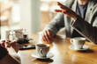 © Comeback Images - Closeup hands of two unrecognizable male business partners having business talk over espresso coffee sitting at table in cafe