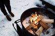 © Alex Domarco/ADDICTIVE STOCK - High angle of crop unrecognizable traveler standing on snow and warming up near camping fireplace with burning firewood in winter day