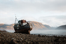 Old Rusty Fishing Boat Moored On Beach In Foggy Morning In Scottish Highlands