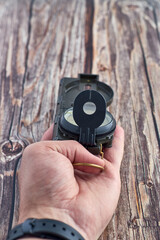 Top view closeup of a person holding an opened compass on a wooden table