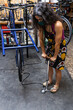 © David Fuentes/ADDICTIVE STOCK - Full length of adult ethnic female mechanic inflating bicycle tire with pump while working in professional workshop