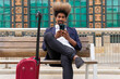 © David Munoz/ADDICTIVE STOCK - African man in suit using his mobile phone sitting in a wooden bench