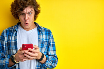 Wall Mural - man is surprised by news on smartphone, stand emotionally reacts on someting he read, hold smartphone in hands