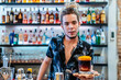 © Javier De La Torre/ADDICTIVE STOCK - Stylish male bartender with dreadlocks standing at counter in bar with cold alcohol cocktail and looking at camera