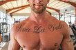 © Javier De La Torre/ADDICTIVE STOCK - Crop smiling male athlete with tattoo on muscular naked chest standing in modern gym