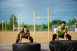 © Georgii - Couple exercising with tyres outside, Young girl and sports instructor training. Power workout outdoors