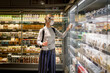 © Maskot - Female customer reading ingredient on product while shopping in supermarket during COVID-19