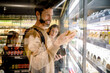 © Maskot - Smiling customer reading ingredients while shopping with family in supermarket