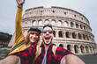 © Davide Angelini - Happy couple visiting Colosseum in Rome, Italy. Friends takes selfie at Coliseum.