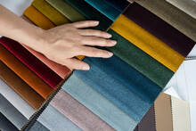 A Woman's Hand Lies On A Catalog Of Fabrics Of Different Colors, A Woman Chooses A Fabric For New Upholstered Furniture At Home, And She Will Give Old Furniture To The Poor