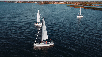 White yachts and a boat sail on dark sea water in the Kaliningrad Bay