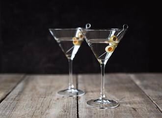 Two classic martini cocktails on wooden table with black background.