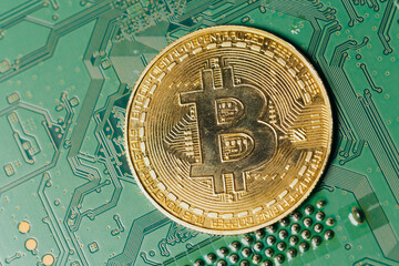Wall Mural - Gold coins with bitcoin symbol on green motherboard.