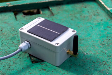 White transmitter with small solar panel and bees monitoring system on green wooden beehive, smart technology iot application