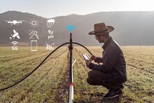 Smart Farming Argriculture Concept. Man Hands Holding A Tablet On Blurred Organic Farm As Background. Smart Irrigation Technology. American Farmer