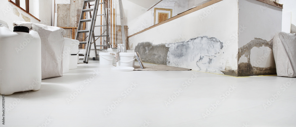Low angle of indoor shot of construction or building site of home renovation with tools with paint buckets and primer jerry can on white floor with copy space - obrazy, fototapety, plakaty 