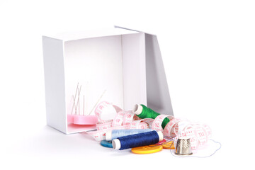 Canvas Print - Closeup shot of sewing accessories falling out of a box on white background