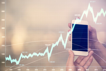 Double exposure of forex graph sketch hologram and woman holding and using a mobile device. Stock market concept.