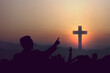 Silhouette of people looking at Christian cross