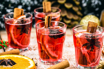 Wall Mural - Mulled red wine with spices and Christmas fruits on a rustic wooden table with Christmas colors and lights. Traditional hot drink at Christmas time