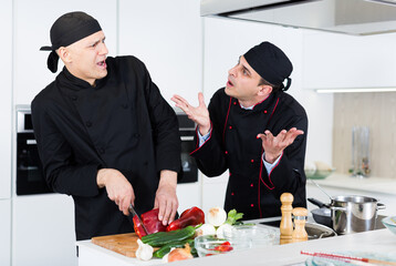 Men kitchener in uniform are emotional cooking salad in the kitchen at the restaurant.