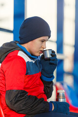 Wall Mural - Boy in soccer sportswear drinks hot water from thermos bottle . Young footballer after game. Training, active lifestyle, sport, children winter activity