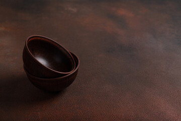 Two dark handmade clay bowls on brown background