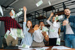 © dikushin - Low-angle shot of cheerful multi-ethnic employees celebrating victory and big profit at office workplace. Cheerful excited young business man and woman throwing away banknote. Rain of money