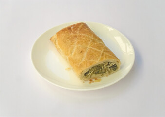 Sticker - homemade vegetable roll on a plate isolated on a white background (puff dough filled with chard)