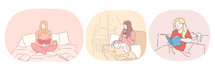 Relaxation with book at home, lazy bedding time concept. Young positive women in comfortable home clothing staying in bed, reading books and relaxing with cat and hot drink at home 