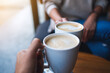 © Farknot Architect - Closeup image of man and woman clinking white coffee mugs in cafe