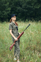 Wall Mural - Woman Green jumpsuit black cap weapon hunting weapons