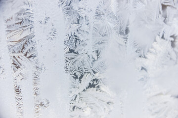 Texture of blue frost on a glass window. Frosty cold weather. White ice patterns texture close-up. New year and Christmas background