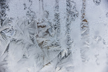 Texture of blue frost on a glass window. Frosty cold weather. White ice patterns texture close-up. New year and Christmas background