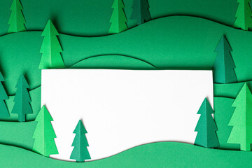 3D pop out Christmas trees paper artwork in green background. Christmas tree paper cutting design card. Top view. Flat lay