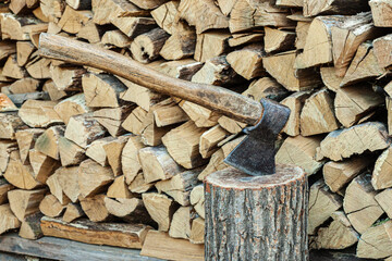 Old ax and a deck for chopping wood. Dry oak firewood stacked in a pile, chopped wood for winter heating of the fireplace. Natural wood background.