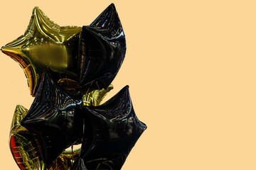 A group of black and gold balloons on a beige background with copy space