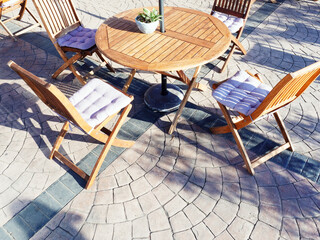 A wooden table and chairs street cafe stand on the ground with granite tiles