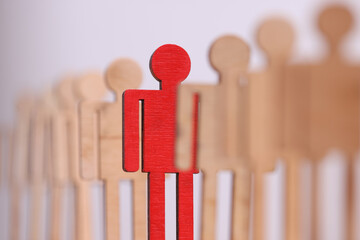 among group of wooden toy men there is one red in line closeup. observance of distance for preventio