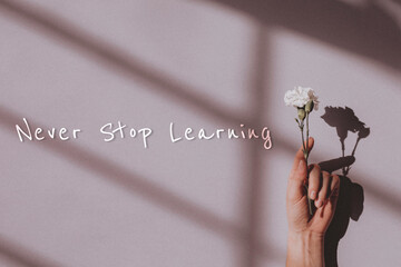 Wall Mural - Never stop learning quote on a hand holding flower background