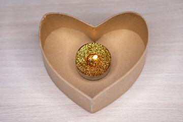 Canvas Print - Closeup shot of a candle with golden glitter in a heart-shaped box