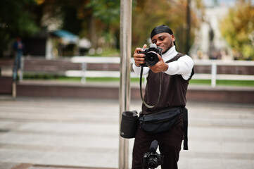 Wall Mural - Young professional african american videographer holding professional camera with pro equipment. Afro cameraman wearing black duraq making a videos.