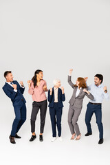 Wall Mural - Positive multicultural businesspeople showing yeah gesture on grey background