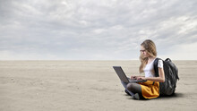 
Young Girl Writes With A Laptop In A Desert