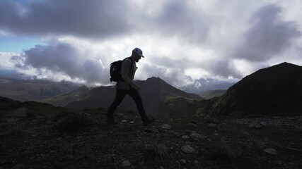 Canvas Print - A hiker walking along a dark rocky mountain ridge on a cloudy day