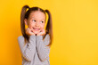 Portrait of young cute adorable smiling girl child kid hold hands under chin isolated on yellow color background