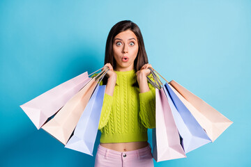 Sticker - Photo portrait of surprised woman holding shopping bags isolated on pastel blue colored background