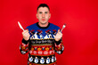 © Roquillo - Young handsome Caucasian man wearing Christmas sweater against red wall,  hungry holding in hand fork knife want tasty yummy pizza pie