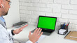 © viacheslav - Doctor man sits on chair at desk in hospital office clinic looking green screen laptop computer talk soothes patient client with breathing technique, online remote health help, social distancing