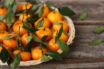 Sticker - Juicy tangerines with green leaves on a wooden table 